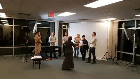 Instructor leading a rehearsal with performers under studio lights