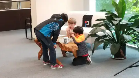 Children gathered around a wooden table playing chess