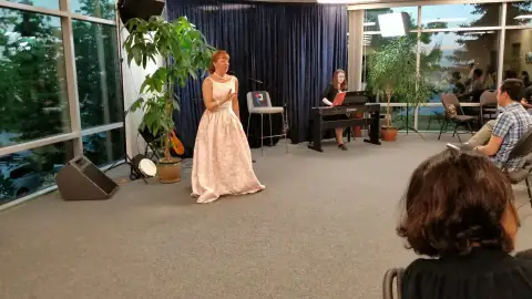 Performer singing in a gown accompanied by a pianist