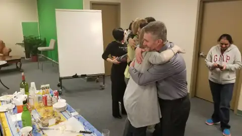 Participants hugging and celebrating near a refreshment table
